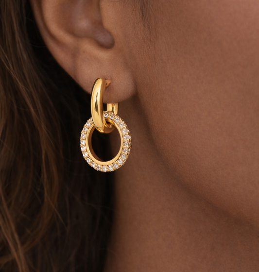 Gold hoop earring with small diamonds worn by a person.