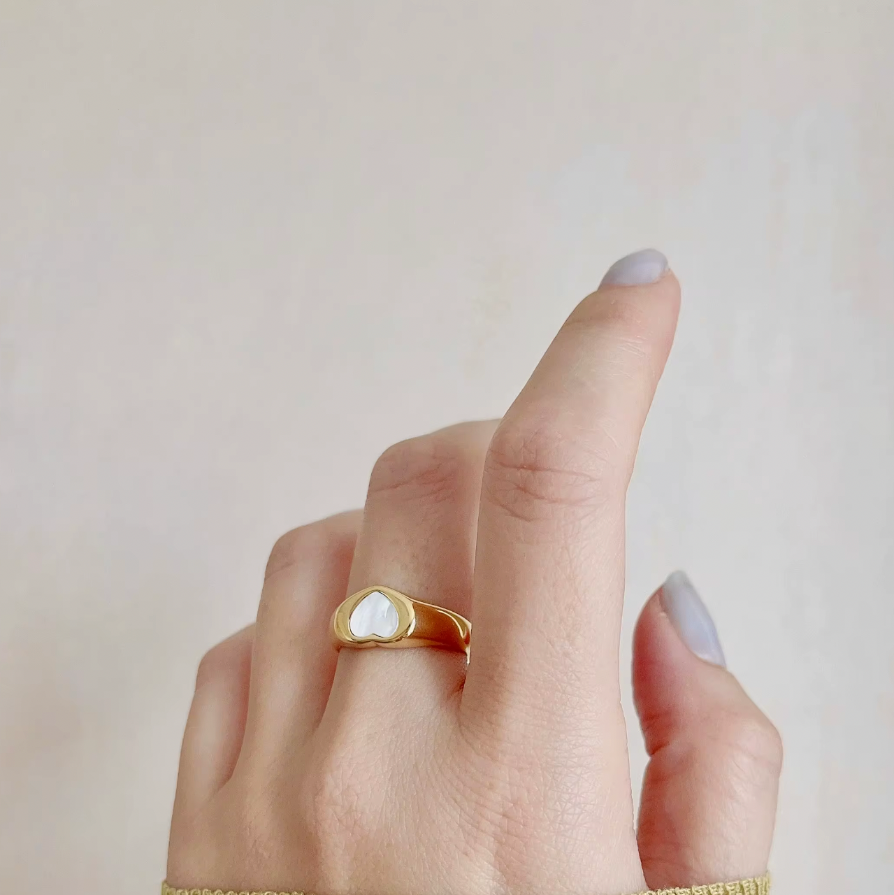 Gold ring on a finger with a plain background