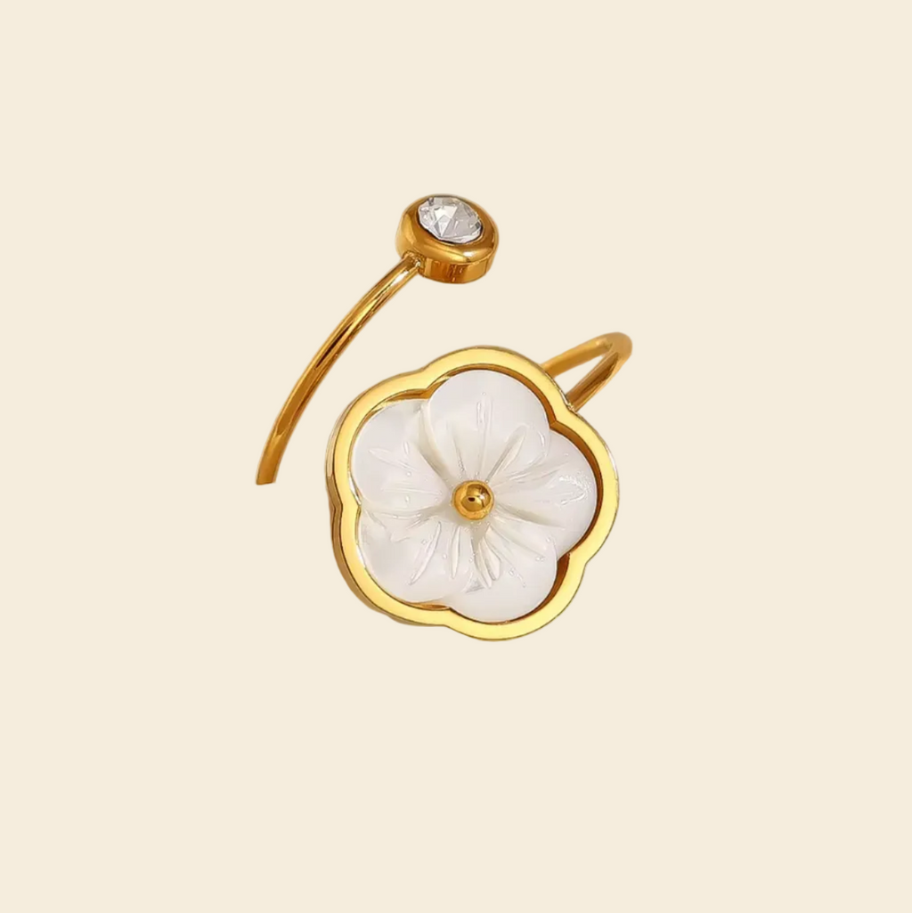 Gold ring with a floral design on a mannequin hand against a beige background