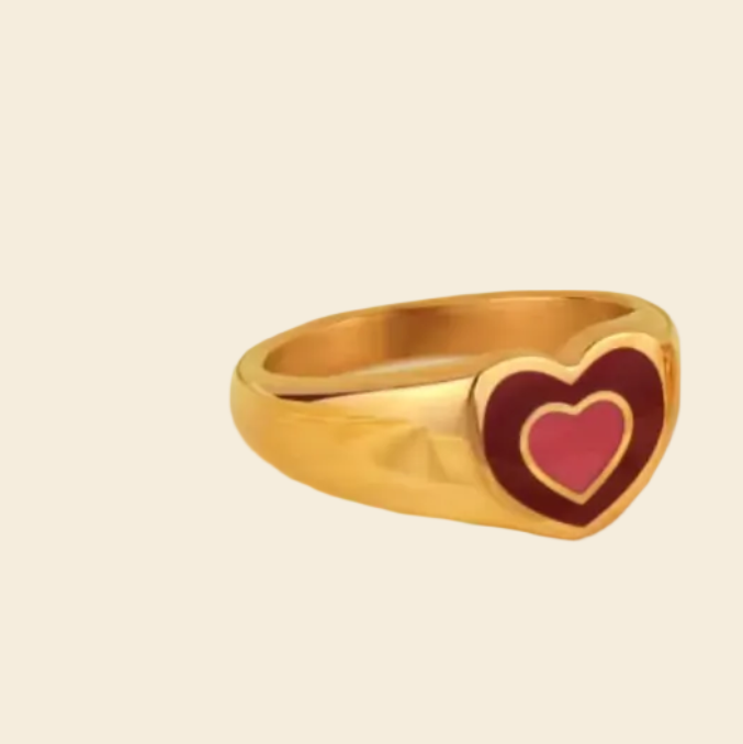 Two gold rings with heart designs on a white plate.