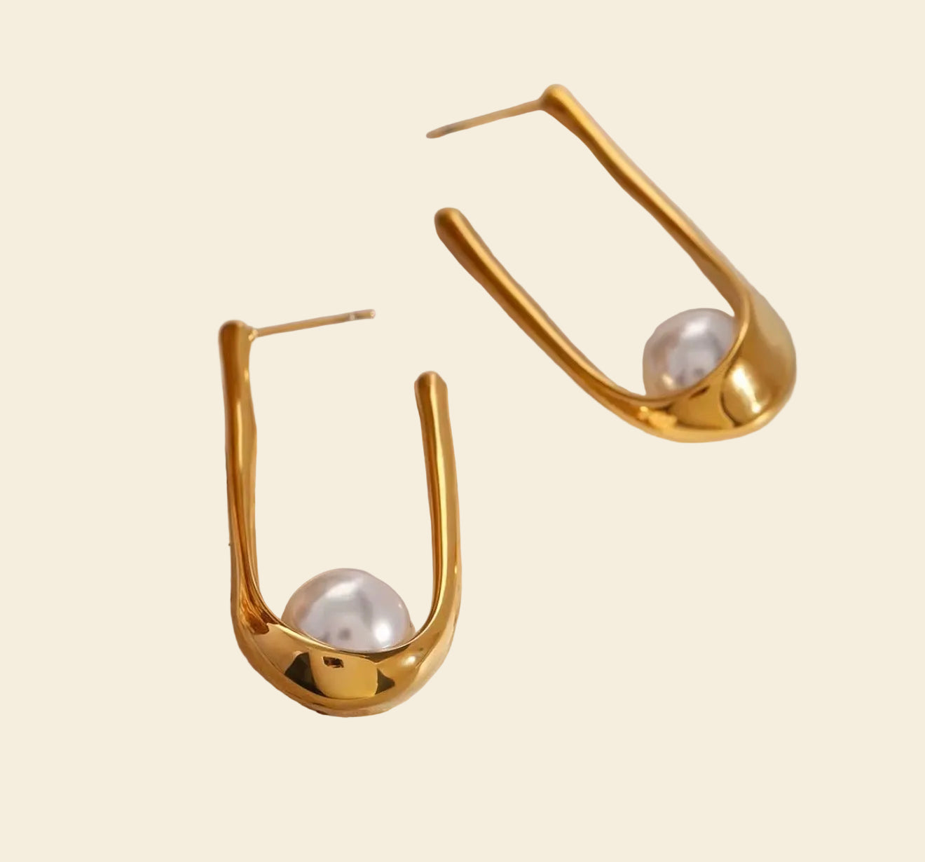 Gold earrings with pearl-like stones on a stone surface