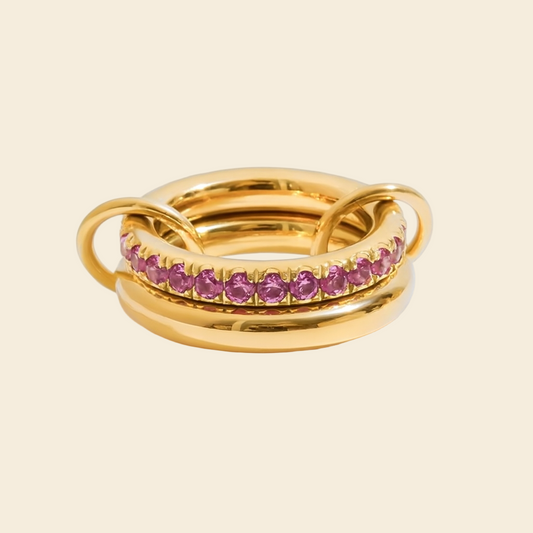 Gold ring with pink gemstones on a white background