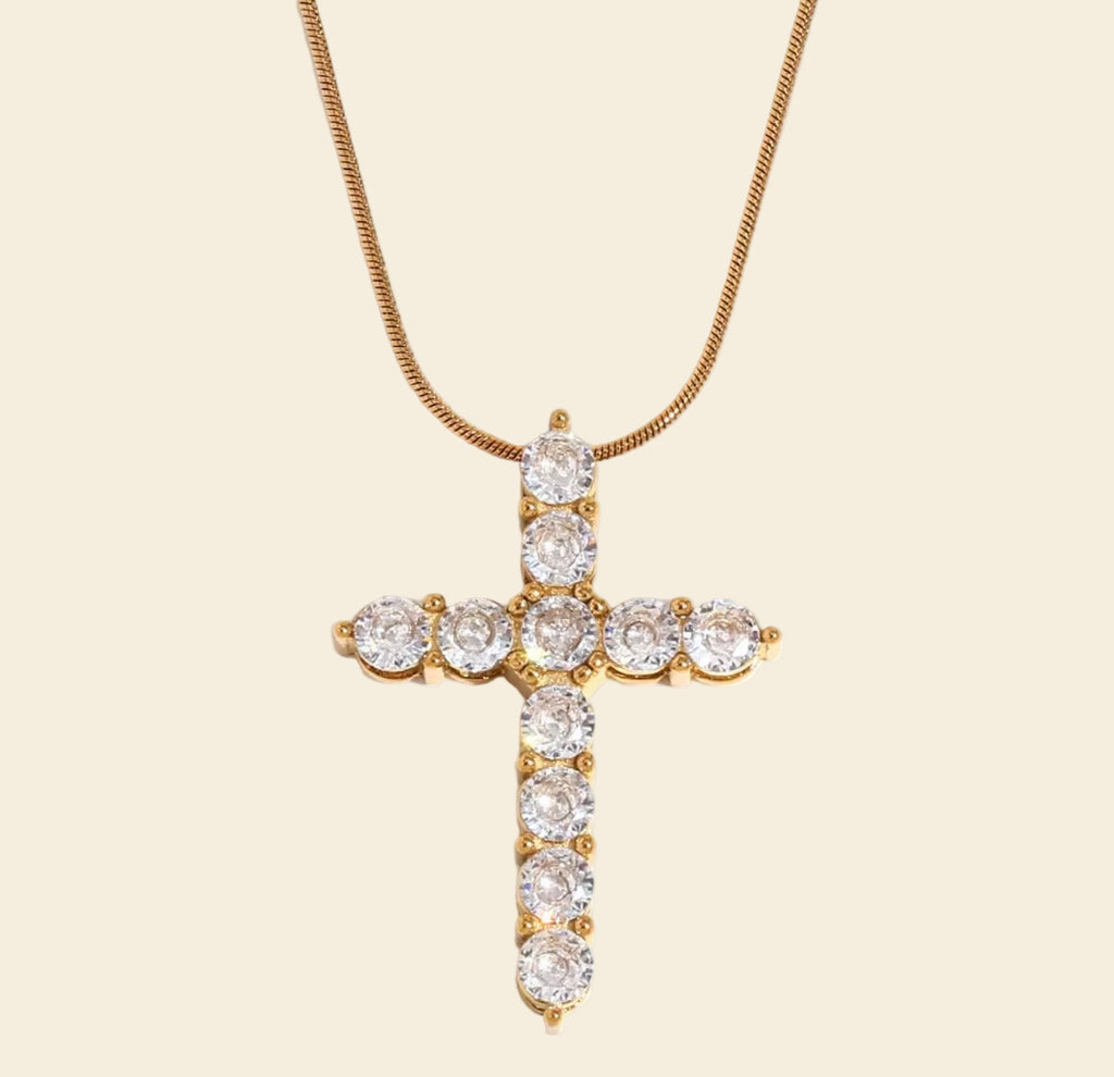 Gold cross necklace with clear stones on a white background