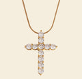 Gold cross necklace with clear stones on a white background