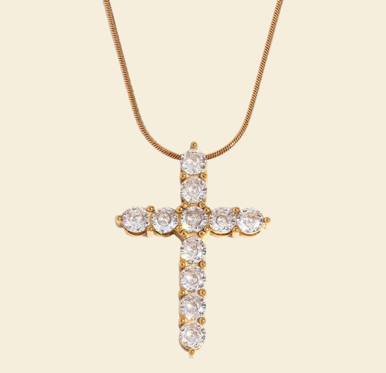 Gold cross necklace with clear stones on a white background