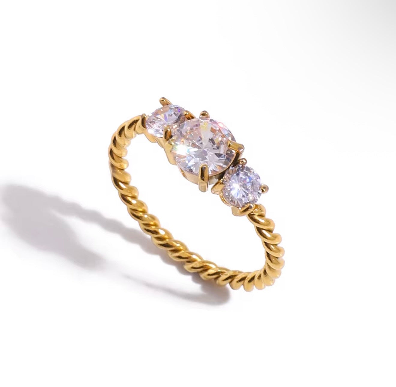 Gold ring with three clear gemstones on a white background