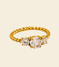 Gold ring with three diamonds on a beige background