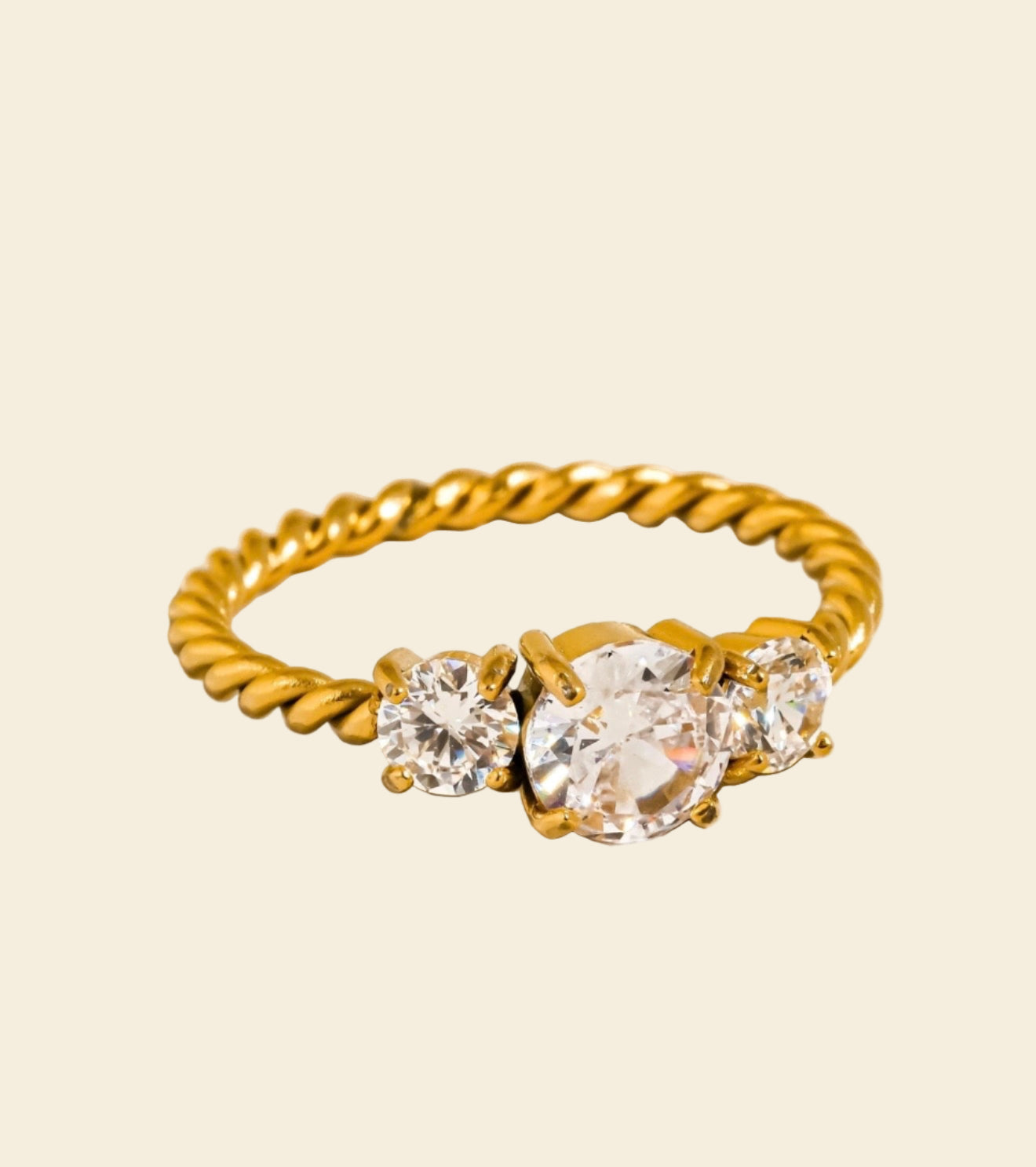 Gold ring with three diamonds on a beige background